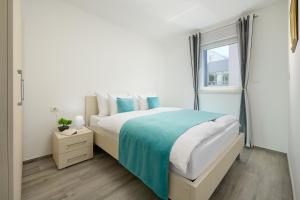 a white bedroom with a bed and a window at Villa Ivano in Makarska