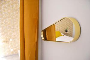 un miroir sur un mur avec un rideau jaune dans l'établissement Hôtel le Thurot, à Dijon