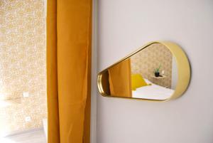 a mirror on a wall with a yellow curtain at Hôtel le Thurot in Dijon