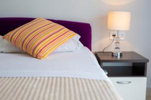 łóżko z kolorową poduszką i stolikiem nocnym z lampką w obiekcie Malinska -Krk w mieście Malinska