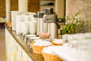 um buffet com produtos de pastelaria e uma bebida no balcão em Pizzato Praia Hotel em Natal