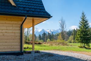 a wooden cabin with mountains in the background at Góralski domek nad Białką in Jurgów
