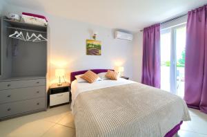 a bedroom with a large bed with purple curtains at Malinska -Krk in Malinska