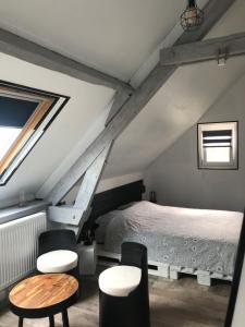 um quarto com uma cama e cadeiras num sótão em Chambre d'hôtes "COQUELICOT" em Nurlu