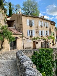 an old house with a stone fence in front of it at La Bouscatière in Moustiers-Sainte-Marie