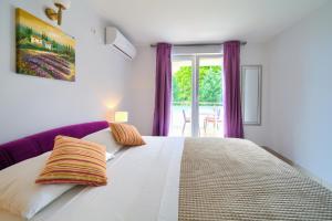 una camera da letto con un grande letto bianco con tende viola di Malinska -Krk a Malinska