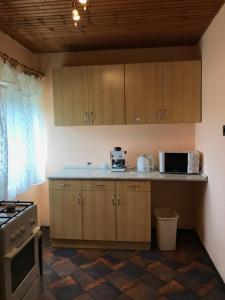 a kitchen with wooden cabinets and a counter top at Szilasi Vendégház in Tüskevár