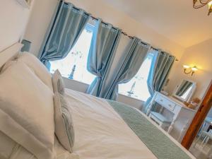 a bedroom with a bed with blue curtains and a window at The Old Dairy in Hickling