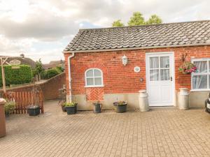 una casa de ladrillo rojo con puerta blanca en The Old Dairy, en Hickling