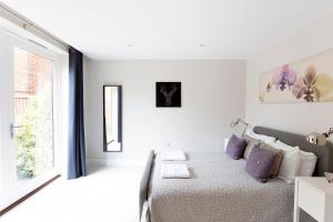 a white bedroom with a bed and a window at Immaculate Central Windsor Town House with parking in Windsor