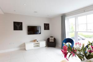 a white living room with a tv on a wall at Immaculate Central Windsor Town House with parking in Windsor