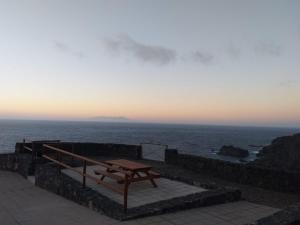 a picnic table sitting on a stone wall near the ocean at Pozo de las Calcosas - El Hierro in Pozo de las Calcosas