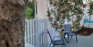 a patio with two chairs and a table and a tree at Chrissi Princess in Skala Sotiros