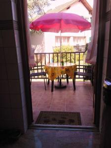 un tavolo con ombrellone rosa su un patio di Colmar Room, Séjour calme chez l'habitant a Colmar