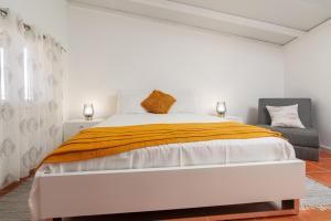 een witte slaapkamer met een bed en een stoel bij Apartment Annie 2 in Arco da Calheta