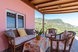 a porch with a couch and chairs and a table at Apartment Annie 2 in Arco da Calheta