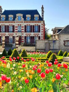 a garden of flowers in front of a building at Demeure de Manneville - SPA - 1Km des plages de Cabourg in Dives-sur-Mer