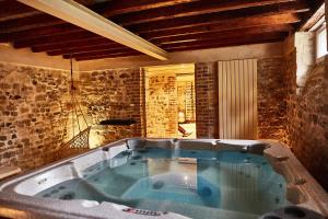 Cette chambre dispose d'une grande baignoire et d'un mur en pierre. dans l'établissement Demeure de Manneville - SPA - 1Km des plages de Cabourg, à Dives-sur-Mer