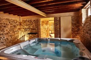 a large bath tub in a room with a stone wall at Demeure de Manneville - SPA - 1Km des plages de Cabourg in Dives-sur-Mer