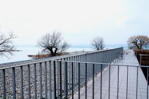 a walkway with a fence and benches on a beach at Club 218 Wellness Luxus Apartman in Siófok