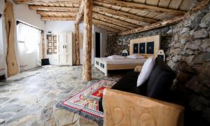 a living room with a bed in a stone wall at Odai din Plai in Moieciu de Sus