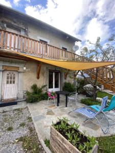 un patio con terrazza e sedie di fronte a una casa di La voûte a Le Noyer