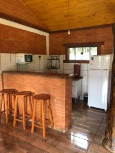 uma cozinha com um balcão com bancos e uma geladeira em Ibitiaçu Chales em Conceição da Ibitipoca