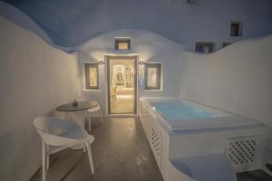 a white bathroom with a tub and a table and chairs at Eternity Suites Santorini in Fira