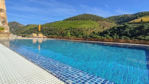 a large swimming pool with mountains in the background at Hotel Casa do Tua in Foz Tua