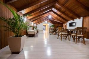 a dining room with wooden ceilings and a table and chairs at Hotel Rouxinol in Piratuba