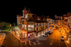 Hotel Rouxinol في بيراتوبا: مدينة في الليل مع سيارات تقف في الشارع