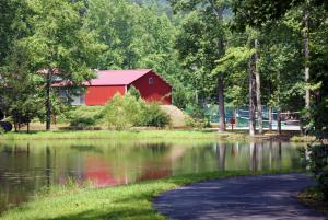 a red barn next to a lake and a road at Alpine Crest Resort, a VRI resort in Helen