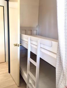 ein weißes Etagenbett in einem Zimmer mit einer Tür in der Unterkunft Rez de jardin + terrasse piscine et accès direct plage (30 mètres !) in Saint-Cyprien
