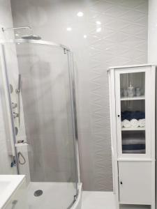 a white bathroom with a shower and a cabinet at Aqua Blue Apartament in Reda
