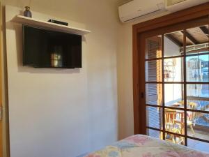 1 dormitorio con TV de pantalla plana en la pared en Aconchegante Apto no Centro de Canela, en Canela