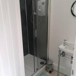 um chuveiro com uma porta de vidro ao lado de um lavatório em Medlyn moor retreats em Porkellis