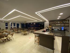 a restaurant with a bar and some tables and chairs at Hotel Rouxinol in Piratuba