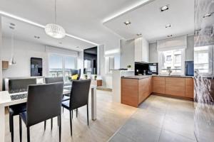 cocina y sala de estar con mesa y sillas en Agapella Apartamenty - Apartament Albatros 15 floor en Gdansk