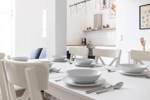 a white dining table with white bowls and chairs at Ferienwohnungen Galerie im Klink in Quedlinburg