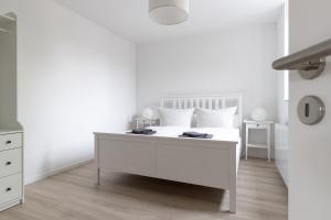 a white bedroom with a white bed with white pillows at Ferienwohnungen Galerie im Klink in Quedlinburg