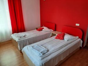 2 camas en una habitación con paredes rojas en Pensiunea Marina, en Bran