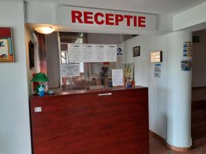 a reception desk in a restaurant with a red sign at Pensiunea Marina in Bran