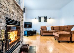 Le Champetre Tremblant 2bdrs Condo W Fireplace في مونت تريمبلانت: غرفة معيشة مع أريكة ومدفأة