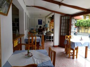 een kamer met tafels en stoelen en een keuken bij Hostal Mario's Rooms in Panajachel