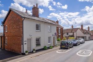 ein weißes Haus mit einem Backsteingebäude an der Straßenseite in der Unterkunft Immaculate luxury retreat in pretty village with great pubs - Box Valley Cottage in Stoke by Nayland