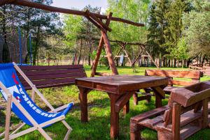 a wooden table and chairs and a picnic table and a bench at Agroturystyka Husinka pl in Husinka