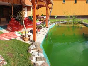 una piscina de agua junto a una casa en Grevia Apartmanok, en Poroszló