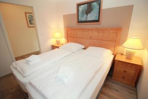 um quarto com uma cama com lençóis brancos e 2 candeeiros em Ferienwohnung Seeblick Plöner See em Ascheberg