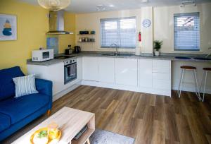 a kitchen with white cabinets and a blue couch at Walking distance to hospital and town with free off-road parking in Bury Saint Edmunds