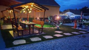 un patio trasero con una mesa y un pabellón por la noche en Grevia Apartmanok en Poroszló
